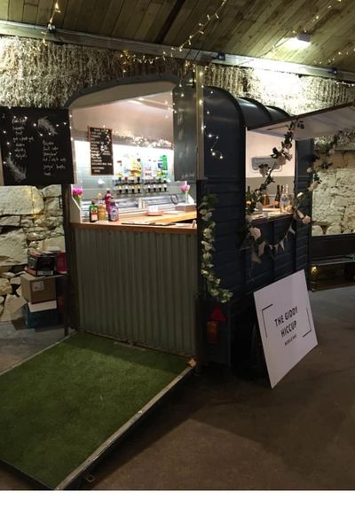 A horsebox which has been converted into a mobile drinks  bar with bottles inside.