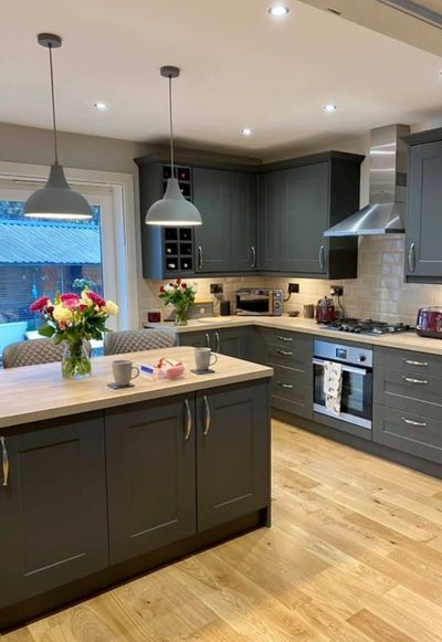 A newly fitted kitchen with grey cupboards and light wood worktops.