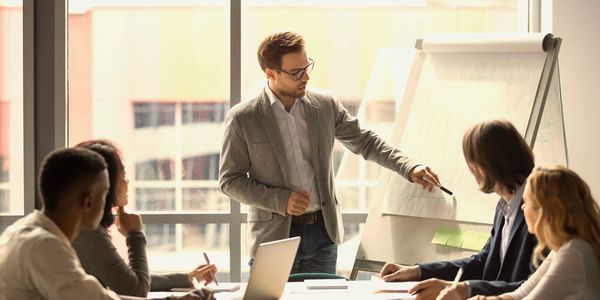 Man presenting ideas to colleagues during a meeting in a bright office.