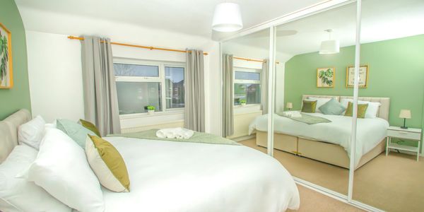 Bright bedroom with green accents and mirrored wardrobe doors.