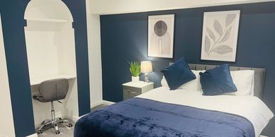 Modern bedroom with navy blue accents and a cozy bed.