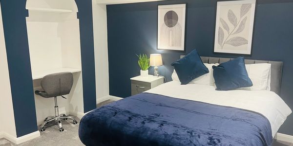 Modern bedroom with navy blue accents and a cozy bed.