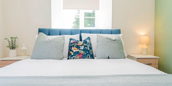 Cozy bed with decorative pillows and soft lighting.