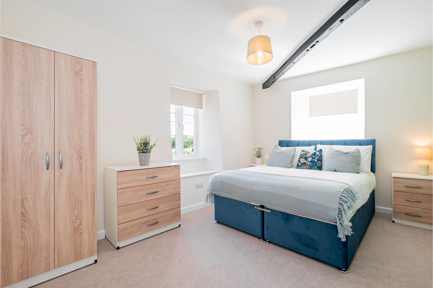 Bright bedroom with blue bed and wooden furniture.