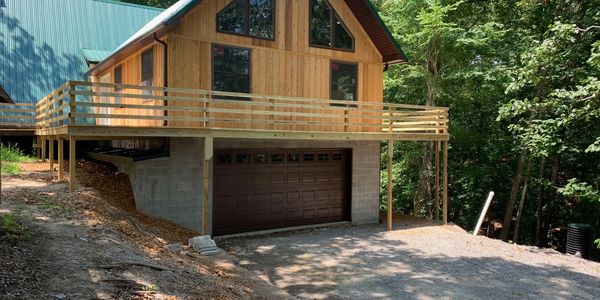 Wood cabin addition of deck and underground garage for extra storage and parking located in Mayfield