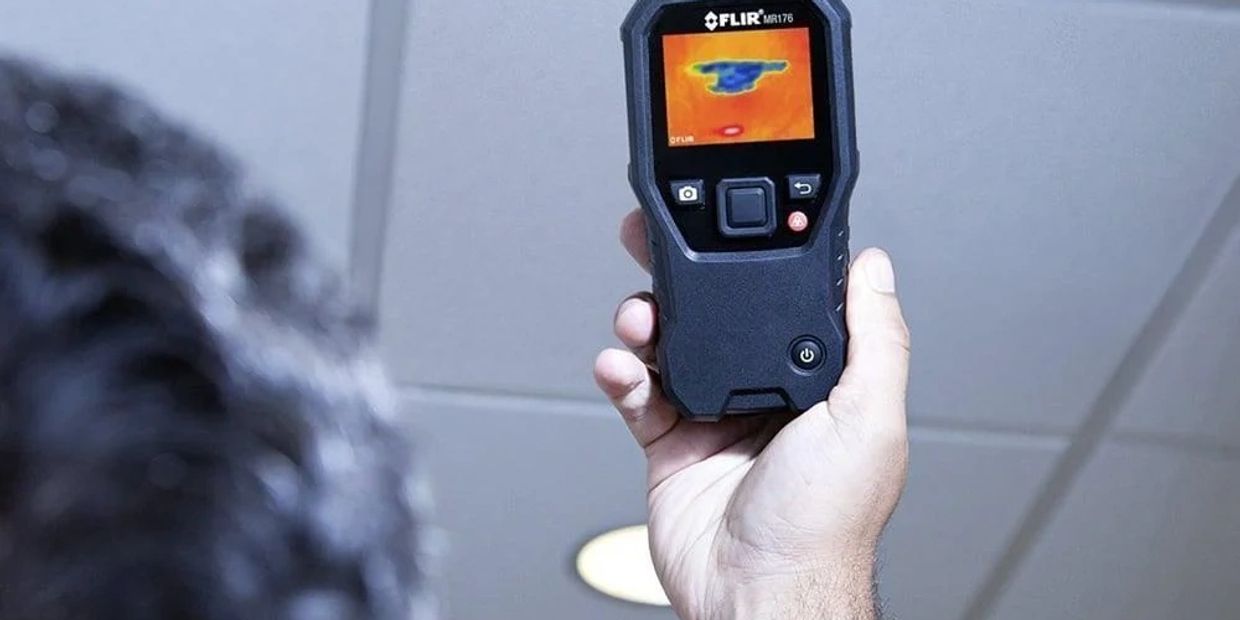 Man using thermal imaging to detect water damage in ceiling in a Western Kentucky home's basement.