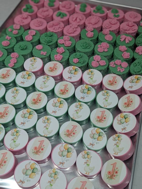 Colorful decorated treats arranged neatly on a tray for a first birthday celebration.