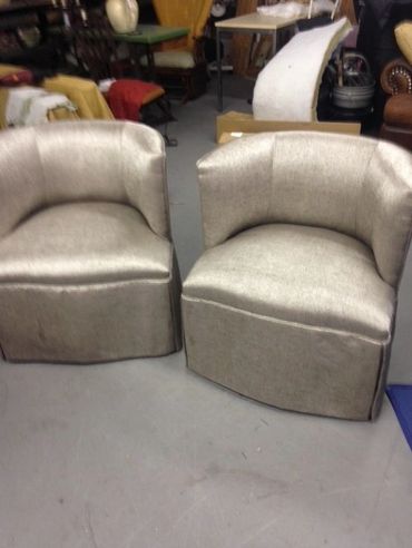 Two silver metallic upholstered armchairs with curved backs.