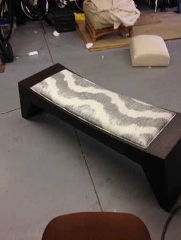 Modern wooden bench with a patterned cushion in a workshop.