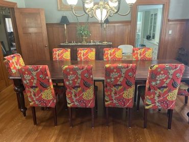 Dining room with vibrant, floral-patterned chairs around a wooden table.