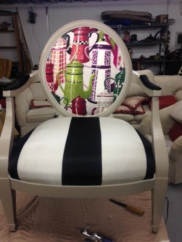 A chair with a colorful teapot pattern on the backrest and black-and-white striped seat.