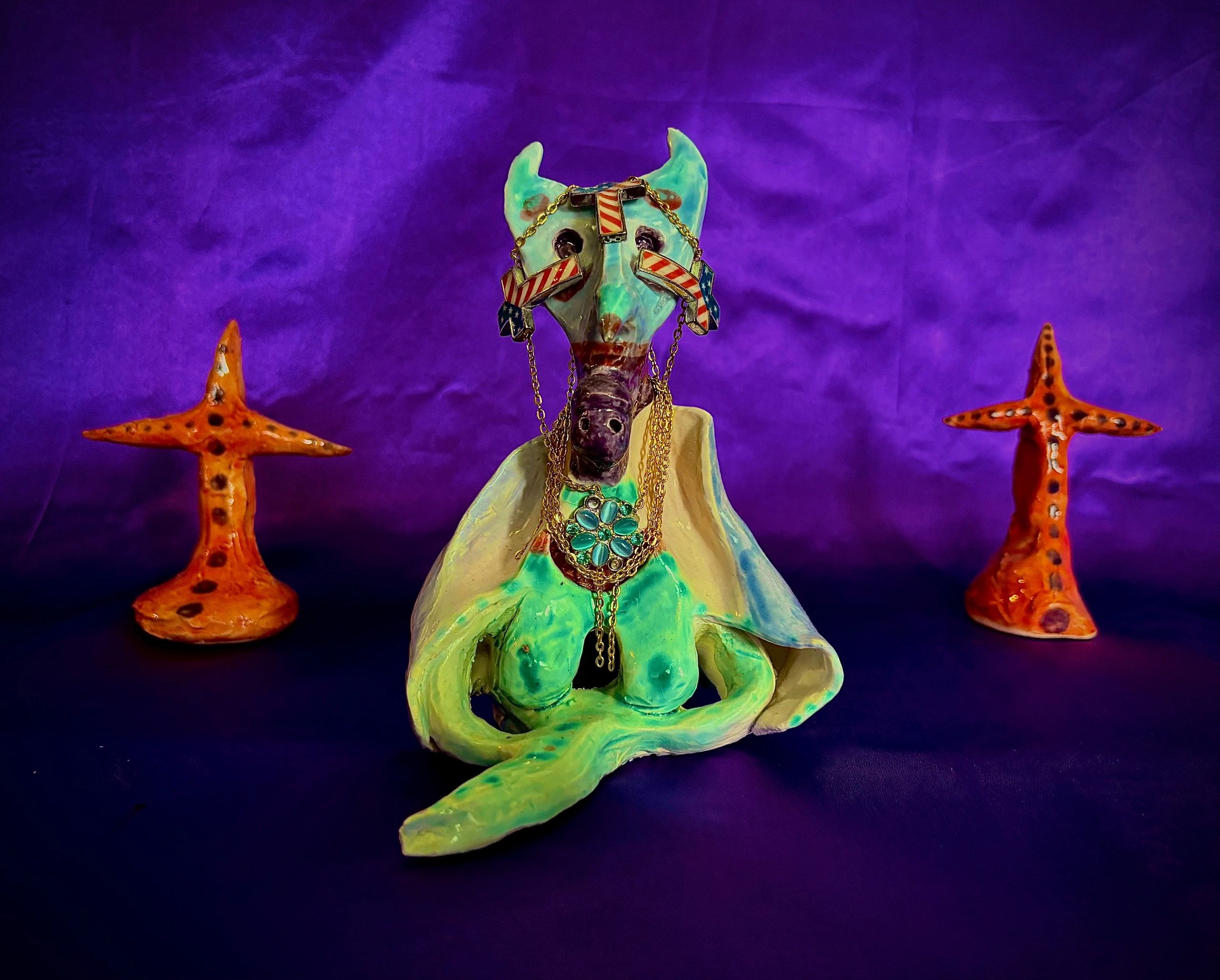 Ceramic figure with star-shaped accessories on purple background.