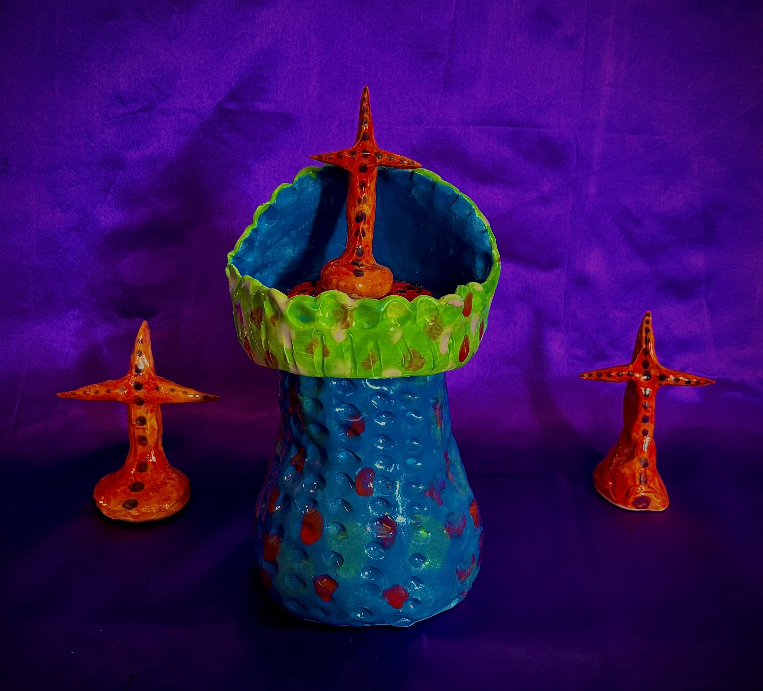 Colorful clay art with starfish shapes on a purple background.