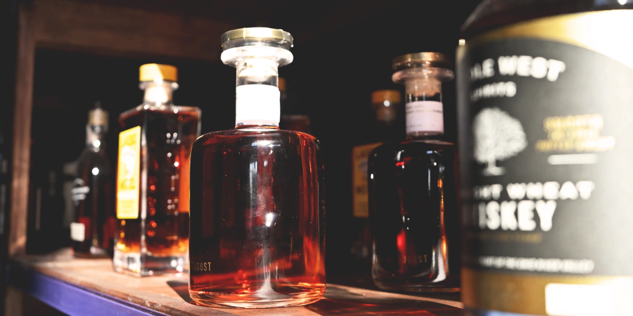 Bottles of whiskey on a wooden shelf.