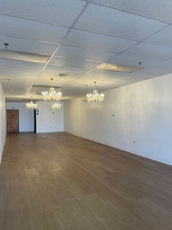 Empty room with chandeliers and wooden floor.