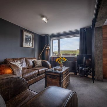 Cozy living room with leather furniture and rustic decor.