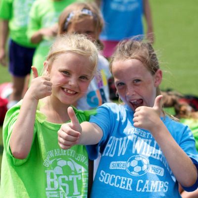 Two girls smiling with two thumbs up at soccer camp