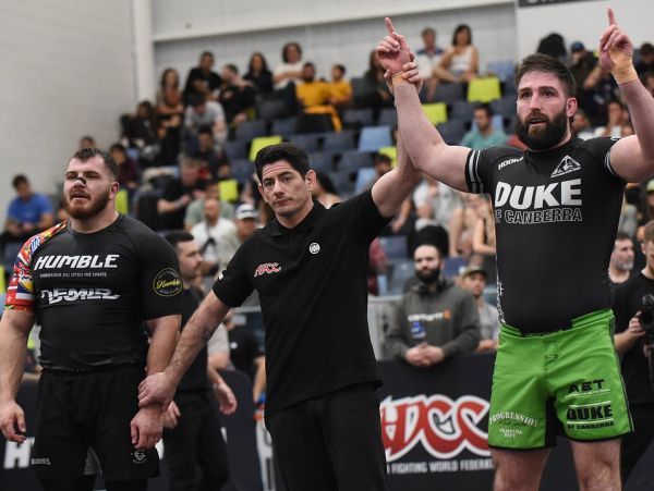 Two fighters and a referee announce the winner in a competition.