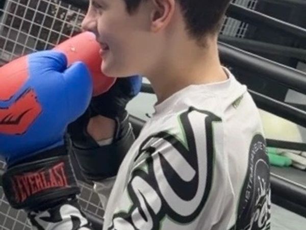 Young boxer with blue gloves smiling.