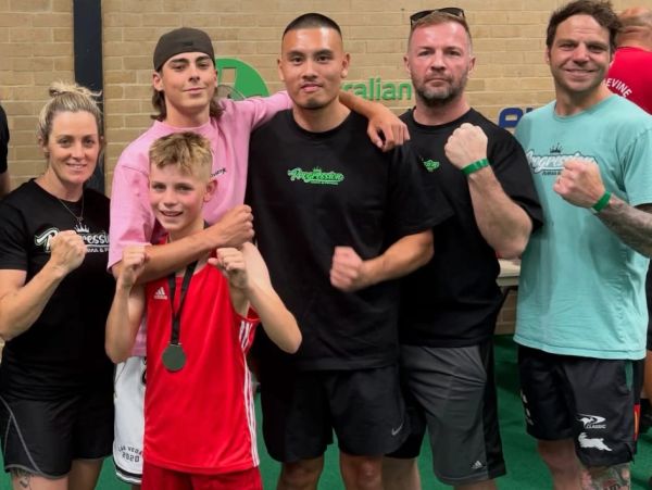 Group of six people posing with fists up in a gym.