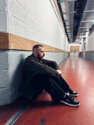 Man sitting alone against a wall.