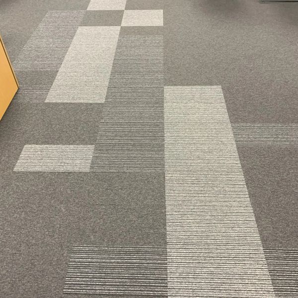 Carpet tiles of grey shades laid in a patterned finish