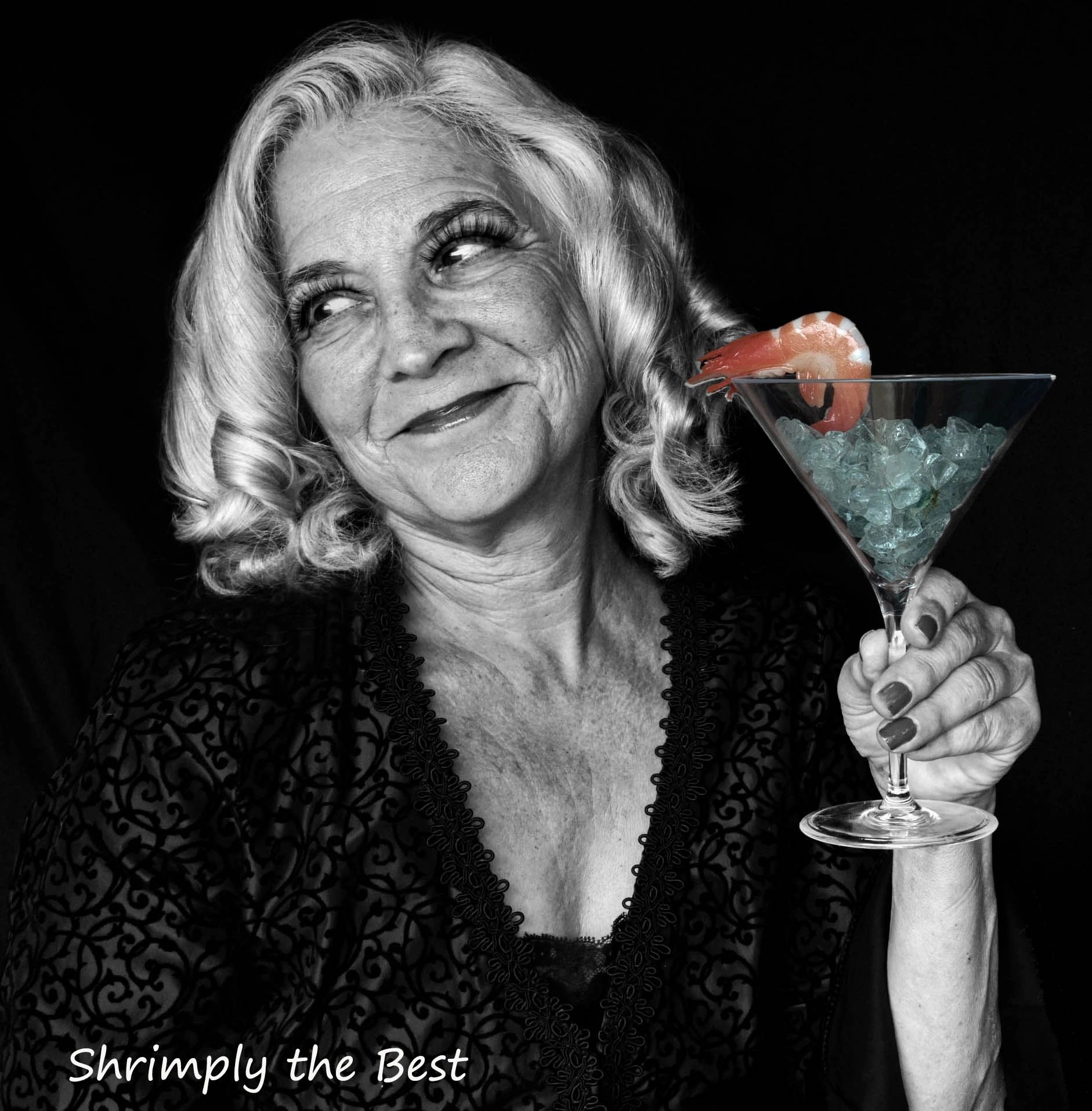 Elderly woman holding a shrimp cocktail glass with a playful smile.