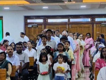 Group of people, including children, gathered indoors.