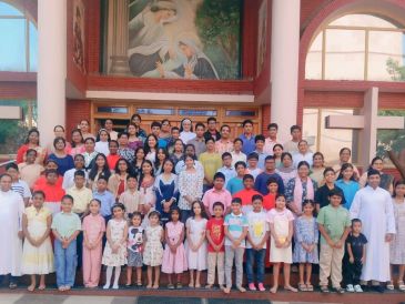 Large group photo of children and adults in front of a building.