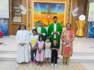 Group photo in a church with children, clergy, and a nun.