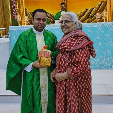 A priest and a woman smiling with a gift in a church.