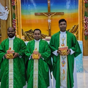 Three priests in green vestments holding gifts inside a church.