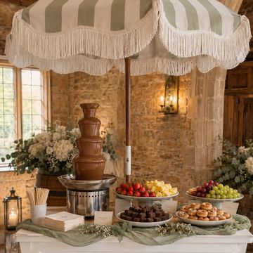 Elegant chocolate fountain dessert table with fruits and pastries.