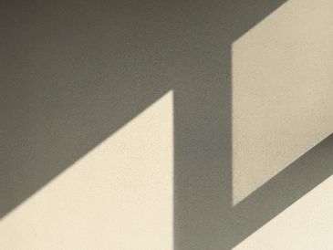 Abstract geometric shadows cast on a textured wall and floor.