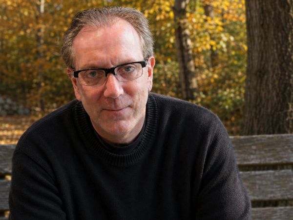 Middle-aged man with glasses outdoors in fall.