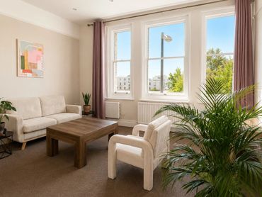 Bright living room with beige furniture and large windows.