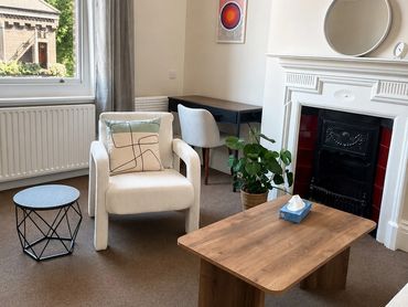 Cozy living room with white armchair, wooden coffee table, and fireplace.