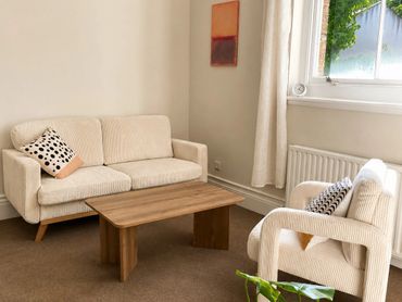 Minimalist living room with beige furniture and a wooden coffee table.