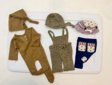 Set of vintage baby clothes and accessories on a white tray.