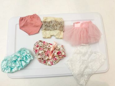 Collection of various baby bloomers and skirts in different colors and styles.