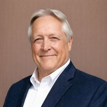 Smiling older man in a navy blazer and white shirt.