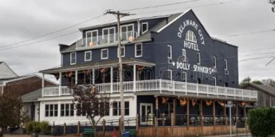 Three-story Delaware City Hotel with wraparound porch and festive decorations.