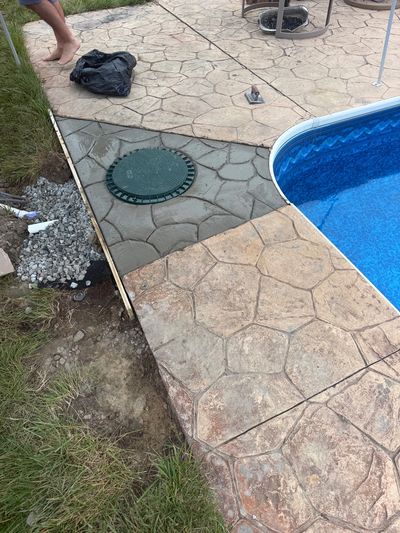 Newly installed stamped concrete around a swimming pool with a green circular cover.