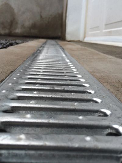 Close-up of a metal drainage grate on a concrete surface.