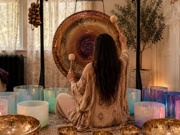 Mujer tocando un gong en un ambiente relajante y espiritual.