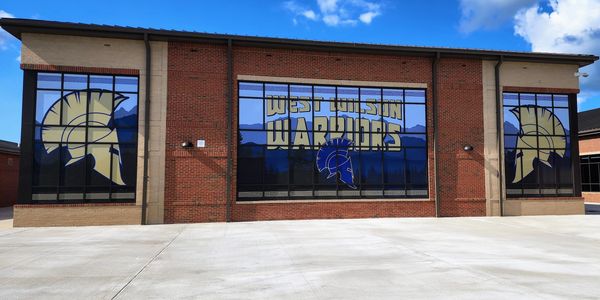Exterior of West Wilson Warriors building with logos.