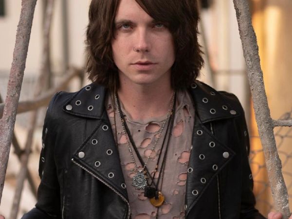 Young man with long hair in a studded leather jacket and distressed shirt.