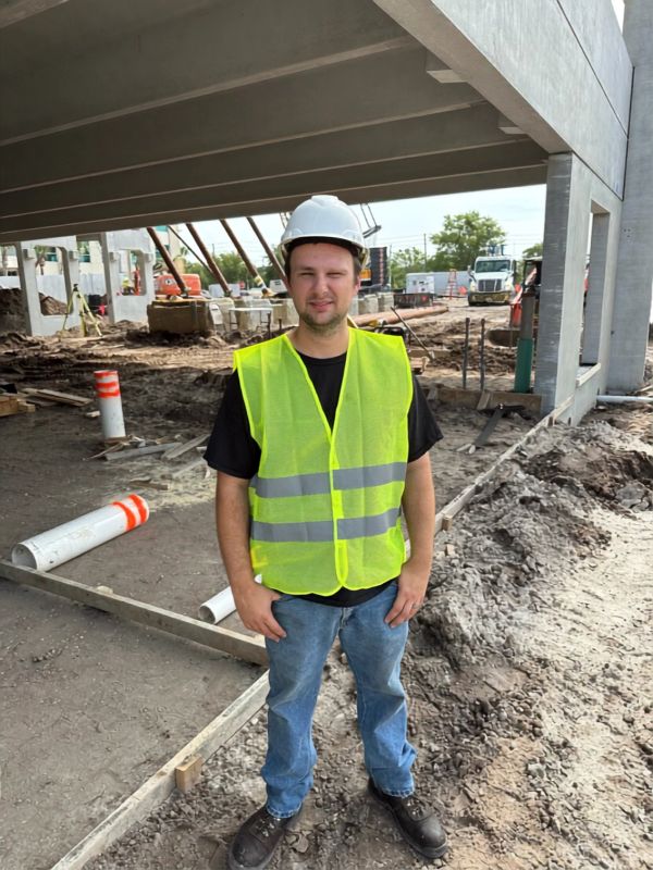 Man in safety vest and helmet at construction site.