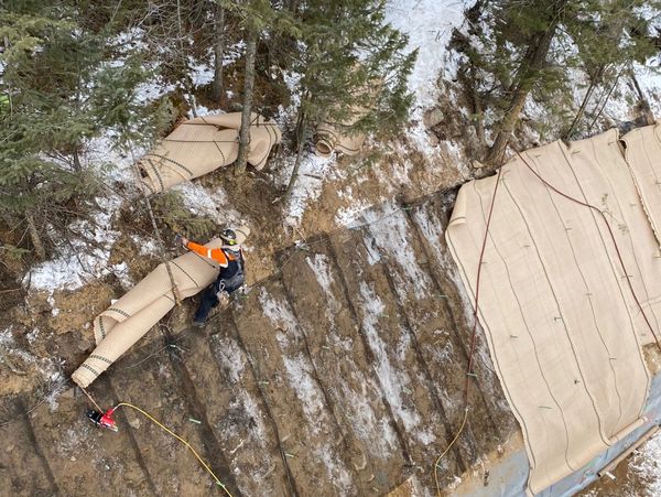 Uinta crew installing a shotcrete-faced soil nail wall on a steep forested slope