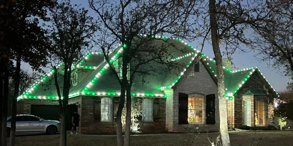 A house decorated with green Christmas lights at dusk.